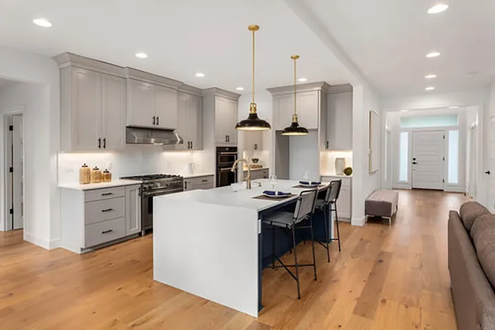 Grey cabinets, white waterfall island and brass pendants