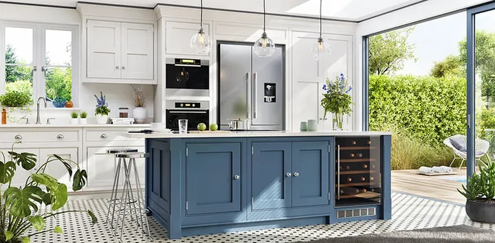 White shaker kitchen with a blue island and wine fridge opening to a garden
